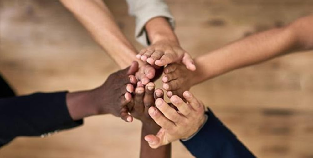 En gruppe mennesker som holder hendene sammen.