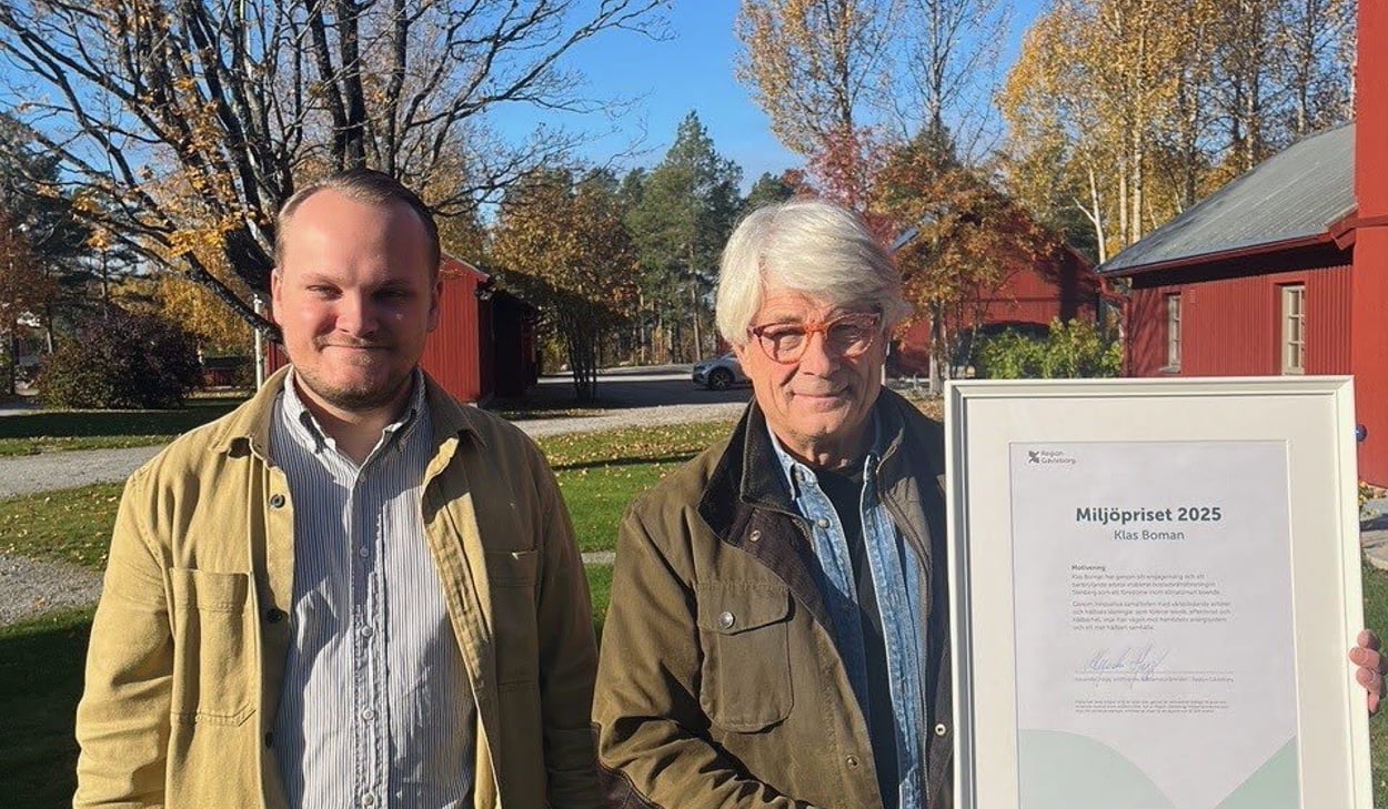 Två män står bredvid varandra i utomhusmiljö på hösten. Den ena håller i ett inramat diplom för Miljöpriset 2025.